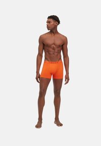 Boxer da uomo in cotone arancione con il logo rosso "FALKE" sulla vita, caratterizzati da un design aderente e una texture liscia.