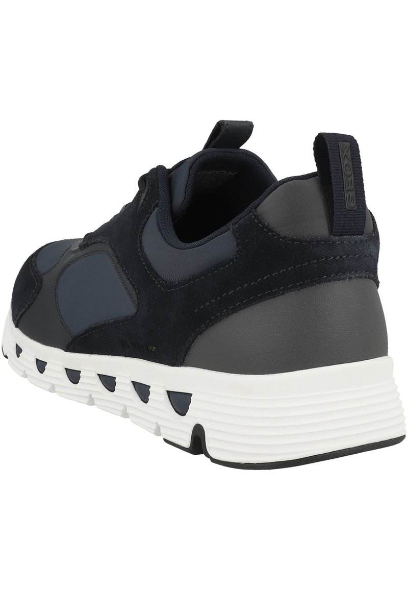 Marineblaue Sneakers aus einer Kombination von Wildleder und synthetischen Materialien, mit einer strukturierten Gummisohle und einer kontrastierenden weißen Zwischensohle mit runden Ausschnitten.