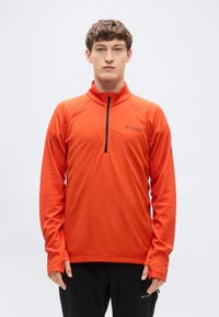 Πορτοκαλί μακρυμάνικο πουλόβερ με γιακά μισού φερμουάρ, υφασμάτινη υφή και λογότυπο στο στήθος. Διαθέτει τρύπ ες για τους αντίχειρες στα μανίκια.