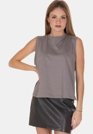 Top grigio senza maniche realizzato in tessuto morbido, caratterizzato da un collo rotondo e una vestibilità rilassata, abbinato a una mini gonna in pelle nera.