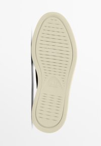 Sole boty z béžového gumového materiálu, s texturovaným vzorem drážek a rýh pro přilnavost a trakci, zakulacený design špičky.