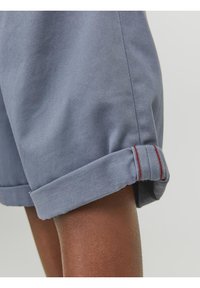 Blauwe katoenen shorts met opgerolde manchetten, met rode accentsteeksels. Het materiaal heeft een gladde textuur en benadrukt het casual ontwerp.