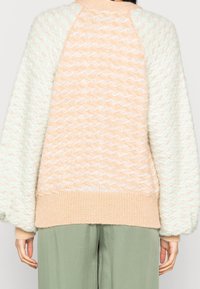 Sweter w pastelowych kolorach, z teksturowanym wzorem dzianiny, z rękawami balonowymi i prążkowanym dołem w kontrastującym beżowym kolorze.
