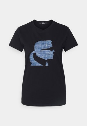 Czarny T-shirt z dekoltem w serek z dużą niebieską teksturowaną sylwetką mężczyzny w okularach przeciwsłonecznych i z kucykiem na środku przodu.