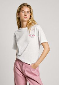 Bílý bavlněný tričko s potiskem "I ♥ London" a "Pepe Jeans" v červené barvě. V kombinaci s růžovými a bílými proužkovanými kalhotami. Volný střih.