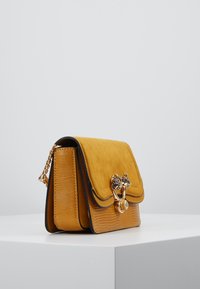 Borsa gialla in suede testurizzato e pelle impreziosita. Dotata di una chiusura in hardware dorato con dettagli decorativi. Cintura a catena attaccata.