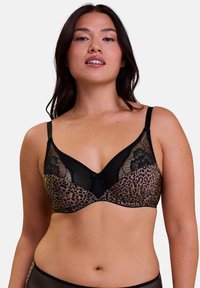 Soutien-gorge en imprimé léopard avec des accents en dentelle noire et un petit nœud au centre. Il dispose de bretelles réglables et d'une texture lisse.