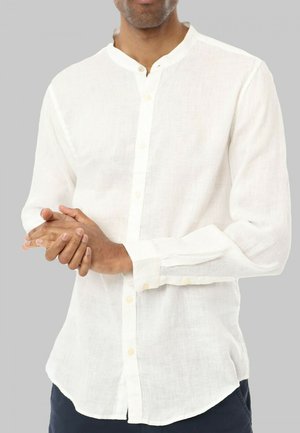 Chemise en lin blanc avec un col montant, des manches longues et une fermeture à boutons. Offre une coupe décontractée et une texture subtile.