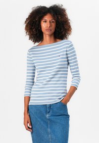Blåstripet langermet topp med båtutringning, laget av mykt stoff. Lite logodetalj synlig på brystet. Brukt med en denimskjørt.