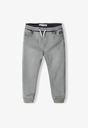 Pantalons de jogging gris avec une taille élastique à rayures noires et blanches, cordon de serrage et poignets côtelés, dotés de poches avant et d'un détail en patch.