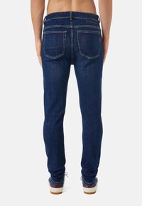 Mörkblå denimjeans med slim fit, som har två bakfickor och kontrasterande gul sömnad. Midjan inkluderar bälteslingor.