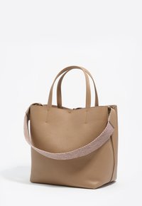 Torba na ramię z jasnobrązowej skóry o usztywnionym kształcie. Posiada dwa krótkie uchwyty oraz teksturowany różowy pleciony pasek na ramię. Brak widocznych metalowych elementów.