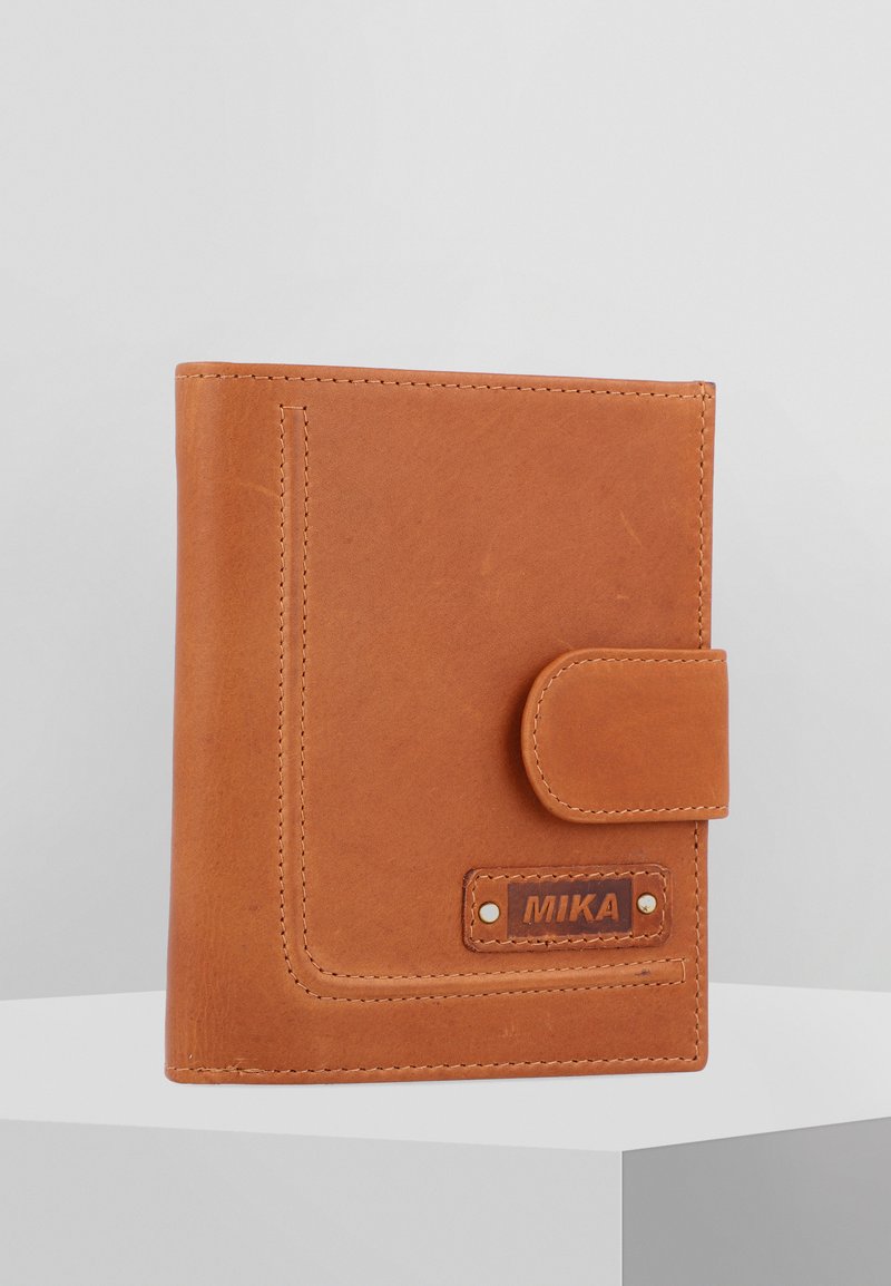 Tan leather wallet with a flap closure, visible stitching, and a branded tag. Features a smooth texture and rectangular shape.