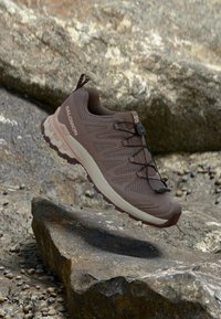 Καφέ αθλητικό παπούτσι με ανώτερο μέρος από διχτυωτό υλικό, υφασμάτινες επενδύσεις και κλειστό σύστημα κορδονιών. Διαθέτει μαξιλαρωμένη σόλα και ενισχυμένη μύτη.