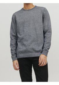 Pull bleu marine à col rond avec un tricot texturé, des poignets et un ourlet côtelés, porté avec un pantalon noir.