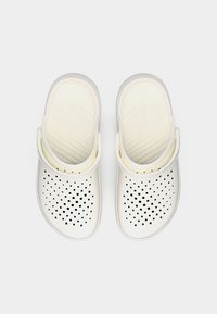 Λευκά καουτσούκ τσόκαρα με διάτρητες πάνω επιφάνειες και ρυθμιζόμενα λουράκια στη φτέρνα, εμφανίζονται από πάνω σε απλό λευκό φόντο.