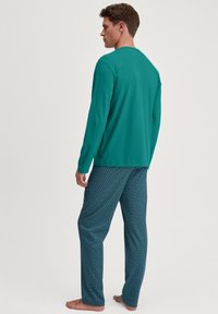 Mouwloze teal top van zachte stof, gecombineerd met gestreepte blauwe pyjamabroek met een golfpatroon, comfortabele pasvorm en elastische tailleband.
