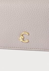 Light gray textured leather wallet with a gold C-shaped logo accent, featuring smooth stitching along the edge.