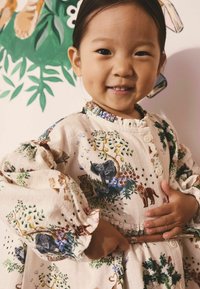 Blumendruckkleid in Creme mit elastischen Rüschenärmeln, das Illustrationen von Tieren und Pflanzen zeigt, sowie dekorativen Knöpfen am Hals.