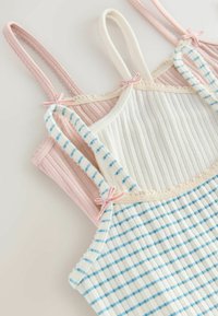Trzy topy na ramiączkach w różowym, białym i jasnoniebieskim wzorze w paski. Posiadają cienkie ramiączka, ribbonową teksturę oraz dekoracyjne kokardki na ramionach.