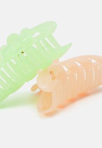 Dois clips de cabelo: um verde translúcido e um pêssego translúcido. Ambos têm um design semelhante a um pente, com seções estriadas e bordas arredondadas.
