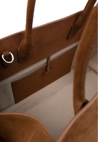 Brun mockask tote-väska med ett slätt, ljust foder; har en ficka för enkel åtkomst och små metallhardware accenter.