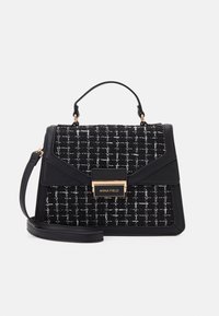 Svartvit tweedhandväska med detaljer i konstläder, platt handtag, justerbar rem och guldfärgad låsmekanism framtill.