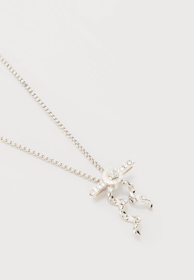 Collier chaîne en argent avec un pendentif en forme de petite silhouette ornée de pierres précieuses claires sur les bras et les jambes.