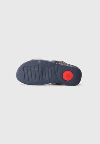 Črna in siva podplat sandala z teksturirano gumo za oprijem. Ima izrazit rdeč poudarek in na dnu odtisnjen logotip "fitflop".