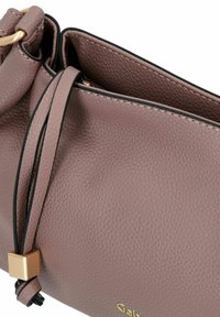 Weiche, rosa Lederhandtasche mit strukturiertem Finish, ausgestattet mit einem oberen Verschluss und goldenen Hardware-Akzenten. Enthält ein dekoratives Kordeldetail.