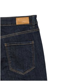 Gesäßtasche einer dunkelblauen Jeans mit orangefarbener Naht und einem braunen Lederetikett mit der Aufschrift "VERO MODA WE DO DENIM."