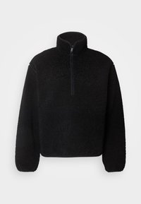 Zwarte fleece pullover met een hoge kraag en een halve rits. Beschikt over een gestructureerd oppervlak en losse mouwen.
