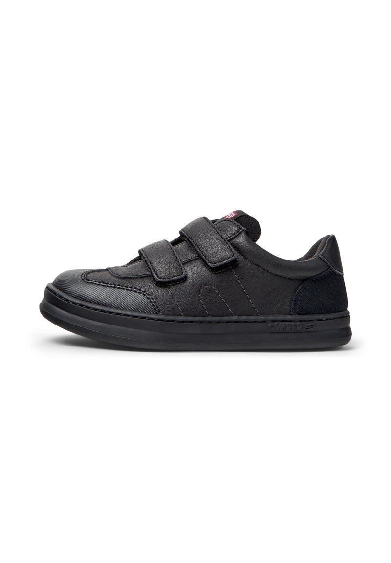 Basket noire avec deux bandes Velcro, fabriquée en cuir et en daim, dotée d'un bout rond et d'une semelle en caoutchouc texturé. Éléments de design minimalistes.