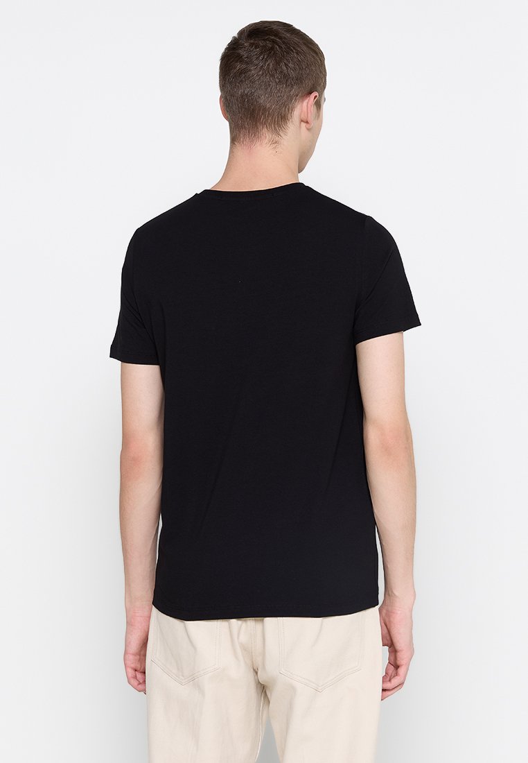 Camiseta de algodón negra con mangas cortas y cuello redondo, vista desde la parte trasera; textura suave, diseño simple, sin patrones ni adornos.