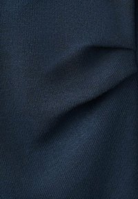 Tessuto a maglia blu scuro con una trama liscia, caratterizzato da sottili variazioni di tonalità e una leggera lucentezza, che crea un aspetto morbido e uniforme.