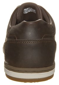Baskets en cuir marron avec un talon arrondi, des coutures grises et une semelle en caoutchouc blanche. Présente une texture lisse et des accents de design minimalistes.
