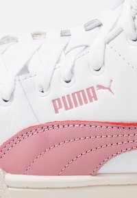 White sneaker featuring pink accents, textured leather, and prominent Puma logo. Laces are white, with silver eyelets for added detail.