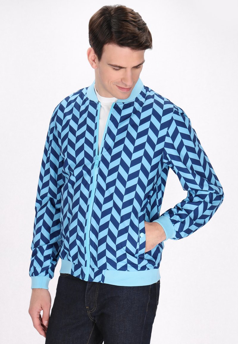 Giacca bomber blu con un motivo a spina di pesce in blu scuro e chiaro, caratterizzata da un colletto e polsini a coste, e una zip frontale.