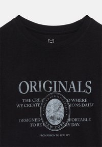 Μαύρο πουκάμισο με λευκό κείμενο "ORIGINALS" και έμβλημα τοπίου βουνών με τ ην επιγραφή "Adirondack Mountains New York" και επιπλέον μικρότερο κείμενο.