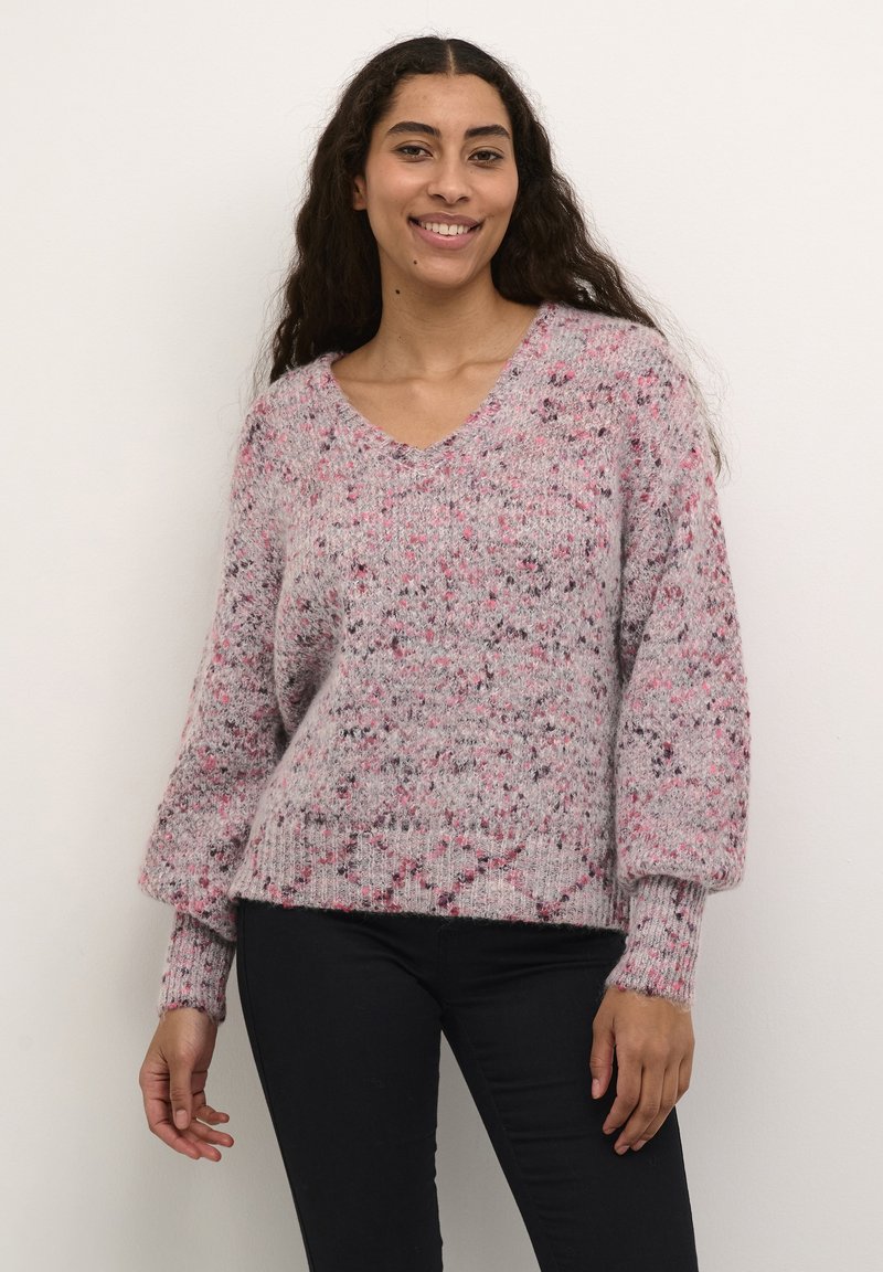 Pulover tricotat roz cu pete, cu decolteu în V, umeri căzuți și manșete cu fâșii bine definite. Țesătură moale, texturată, cu modele de fibre variate.