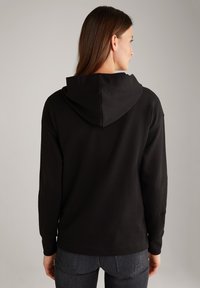 Felpa con cappuccio nera, a maniche lunghe, realizzata in un tessuto morbido. Presenta una vestibilità ampia e un dettaglio del logo ricamato sulla manica.