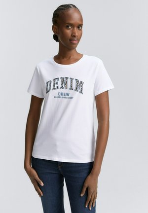 T-shirt en coton blanc arborant "DENIM CREW ÉTABLI EN 2007" en lettres bleu foncé et à motifs ; col rond, manches courtes, coupe décontractée.