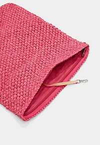 Rosa vävd clutchväska delvis öppen som visar matchande tyginredning och ett randigt handledsband med metalldetalj.