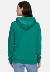 Sudadera verde con un gran bolsillo delantero y capucha con cordón. Hecha de una tela suave, con puños y dobladillo acanalados.