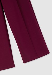 Pantaloni bordeaux a gamba larga in tessuto morbido e liscio, caratterizzati da un design lineare pulito e orli dritti, con dettagli di cuciture visibili.