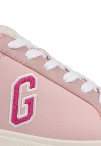 Pink leather sneaker featuring white laces, a textured finish, and a prominent embroidered "G" logo in pink and white accents.