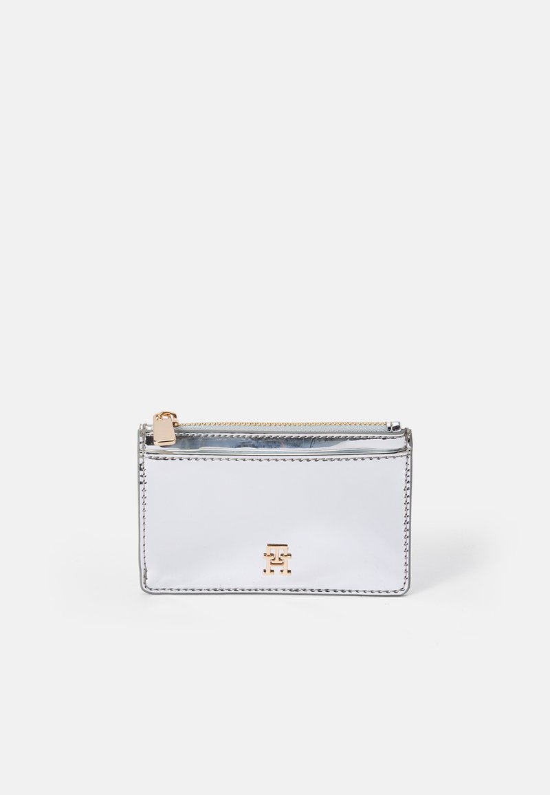Pochette zip in pelle argentata con hardware dorato, forma rettangolare e dettaglio del logo sul davanti. Texture liscia, design minimalista.