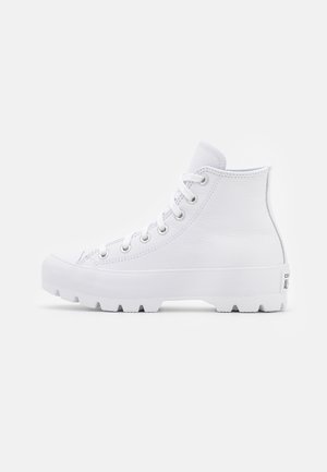 Witte hoge sneaker met dikke zool, veters aan de voorkant en robuust loopvlak, weergegeven in zijaanzicht op een effen achtergrond.