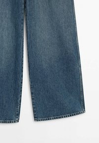 Pantaloni in denim a gamba larga in blu chiaro a medio, caratterizzati da una superficie liscia, una vestibilità dritta e cuciture visibili lungo i bordi.