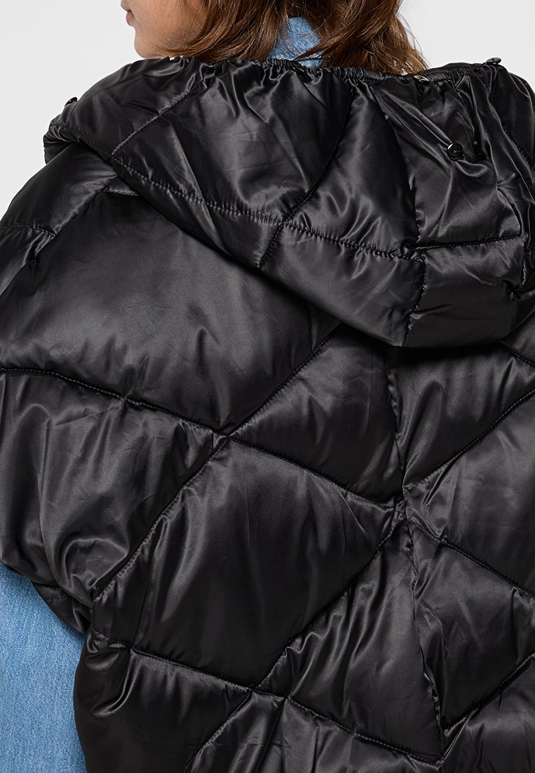 Giacca a vento nera caratterizzata da un design trapuntato, materiale in nylon lucido, cappuccio elasticizzato e dettagli di cucitura visibili.